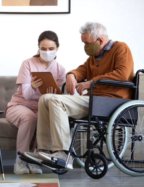 female-caregiver-assisting-senior-man-in-wheelchai-KANACKR